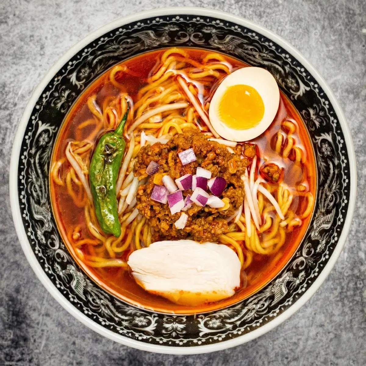 Chicken Spicy - A bowl of bold spicy chicken broth ramen with medium straight noodles, chicken breast chashu, minced spicy chicken, bean sprouts, shishito pepper, and a soft-boiled egg