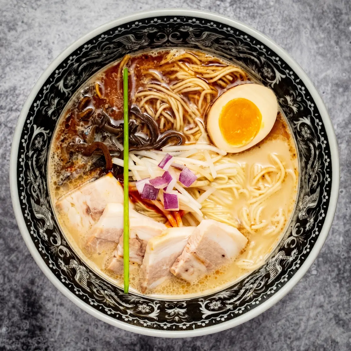 Tonkotsu Gachi - A bowl of well-balanced pork broth ramen with medium straight noodles, pork chashu, black garlic oil, umami paste, kikurage mushroom, bean sprouts, and a soft-boiled egg