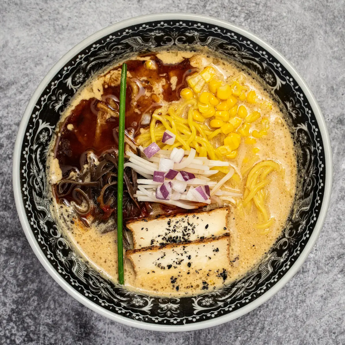 Vegan Miso Gachi - A bowl of miso and sesame broth ramen with thick noodles, tofu chashu, black garlic oil, bean sprouts, corn, kikurage mushrooms, and umami paste